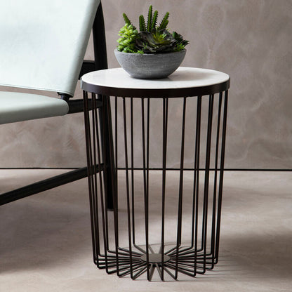 Modern side table with black metal base and white marble top, featuring a potted plant, next to a gray chair.