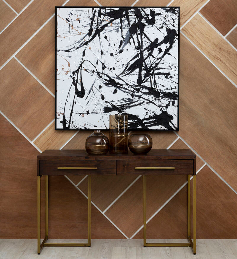 Console table with decorative items against a wall with abstract black and white art.
