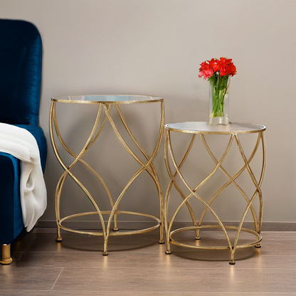 Two gold side tables with glass tops in a room setting.