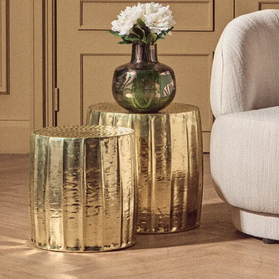 Beige armchair with a small table and vase against a brown paneled wall.