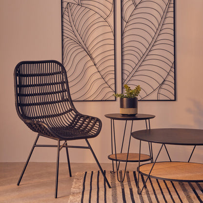 Modern interior with a black wicker chair, small round table, and decorative wall art.