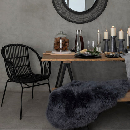 Dining area with a round mirror, table, chairs, and decorative items against a gray wall.