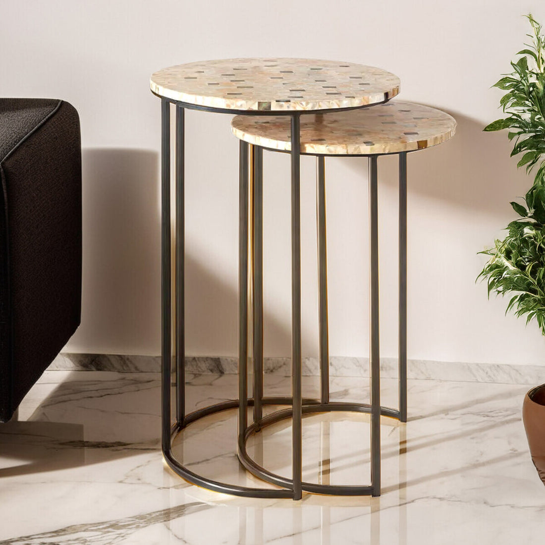 Set of two round side tables with marble tops and black metal frames on a marble floor.