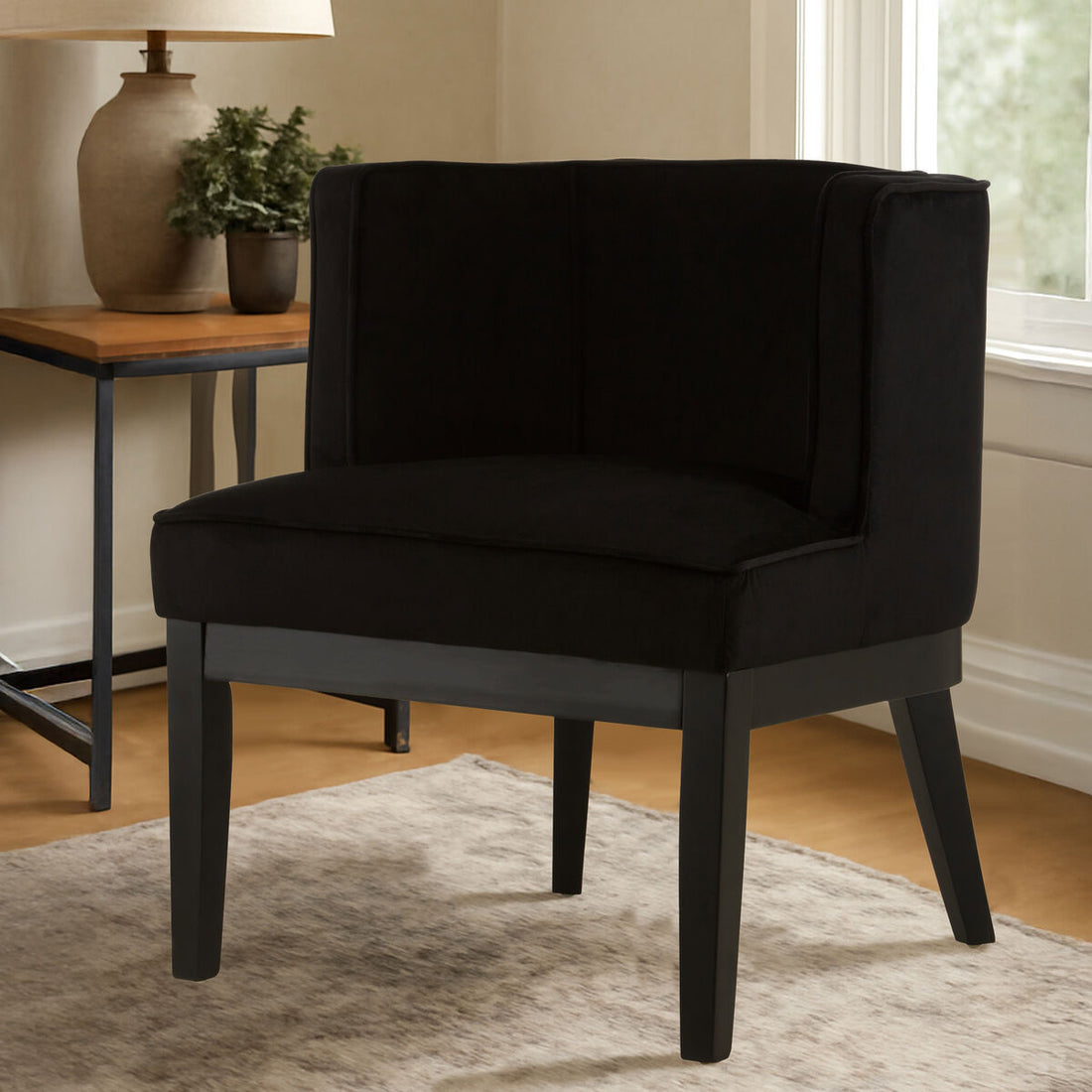Black upholstered chair in a room with a side table and window.