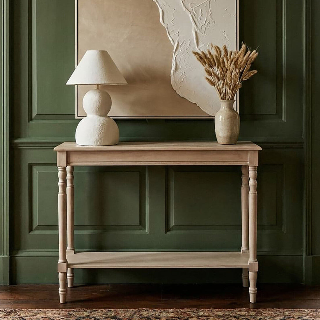Wooden table with a lamp and vase against a green paneled wall