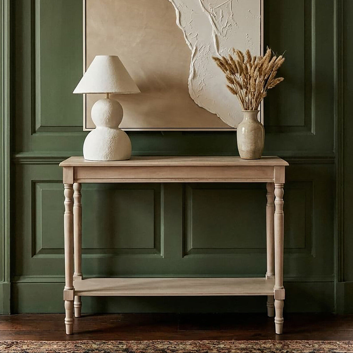 Wooden table with a lamp and vase against a green paneled wall