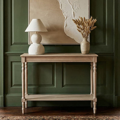 Wooden table with a lamp and vase against a green paneled wall