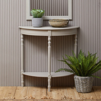 Small wooden console table with a mirror, plants, and a basket against a striped wall.