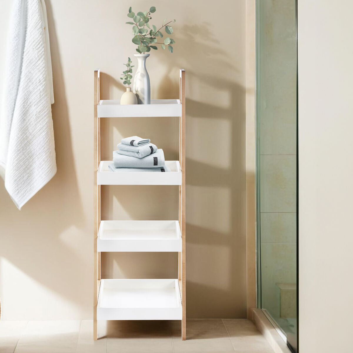 Bathroom shelf with towels and a plant against a beige wall.