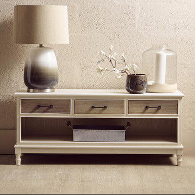 White wooden console table with decorative items against a light gray wall.