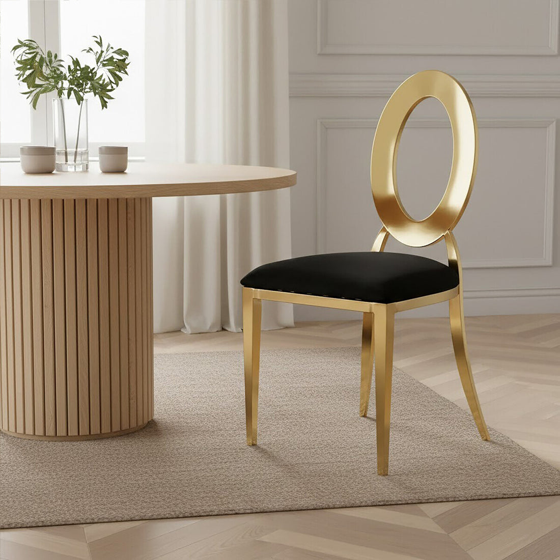 Gold chair with black cushion next to a wooden table in a room with light-colored walls and floor.