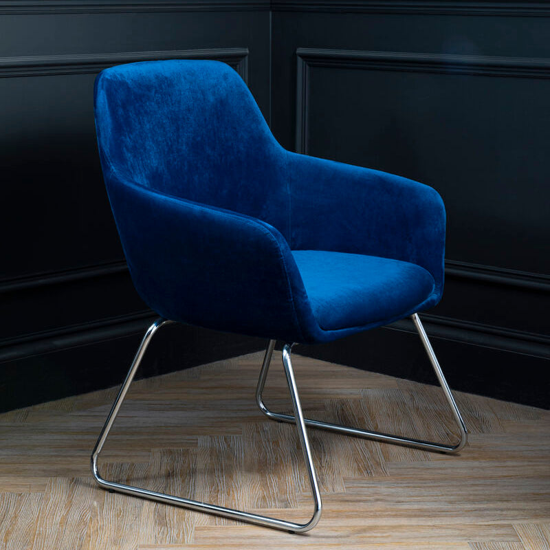 Blue armchair with metal legs against a dark paneled wall.