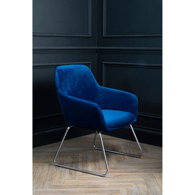 Blue armchair with metal legs against a dark paneled wall.