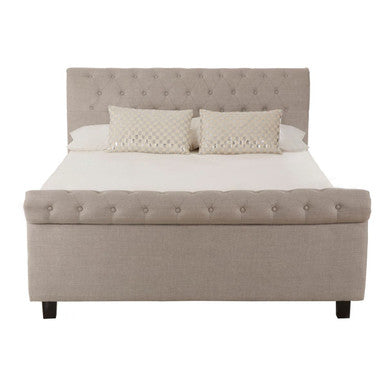 Beige upholstered bed with white mattress and pillows on a white background