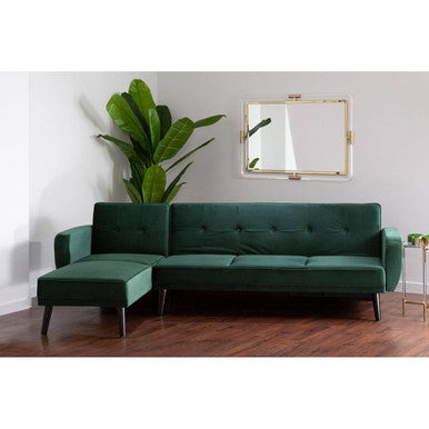 Green sectional sofa in a room with a plant and mirror on the wall.