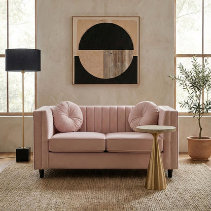 Pink sofa in a living room with abstract art on the wall and a side table.