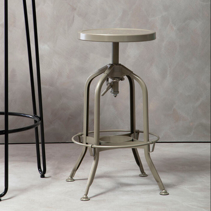 Vintage-style metal stool against a gray textured wall with a black metal table.