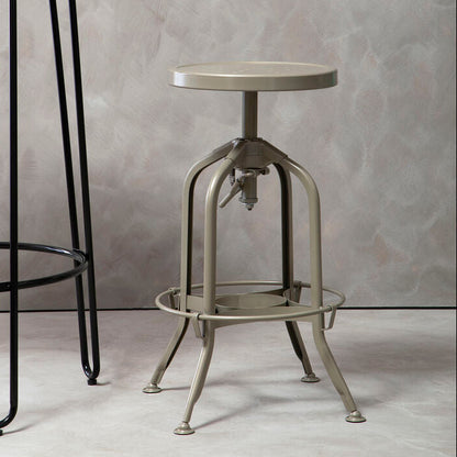 Vintage-style metal stool against a gray textured wall with a black metal table.