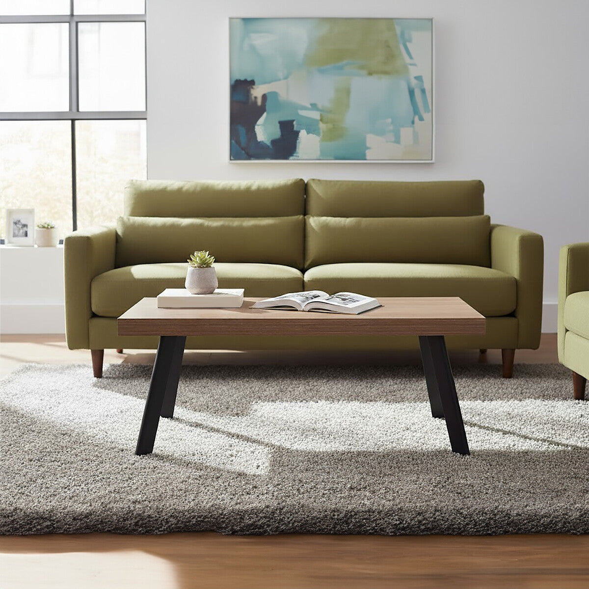Green sofa in a living room with a wooden coffee table and abstract art on the wall.