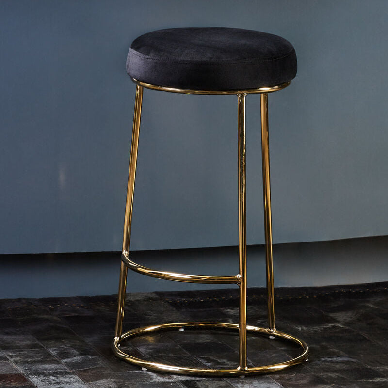 Bar stool with gold frame and black cushion on a blue wall background