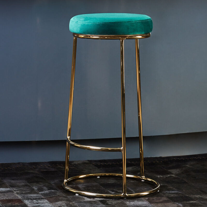 Teal bar stool with gold legs against a blue wall