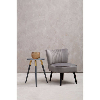 Gray armchair and small round table against a plain wall