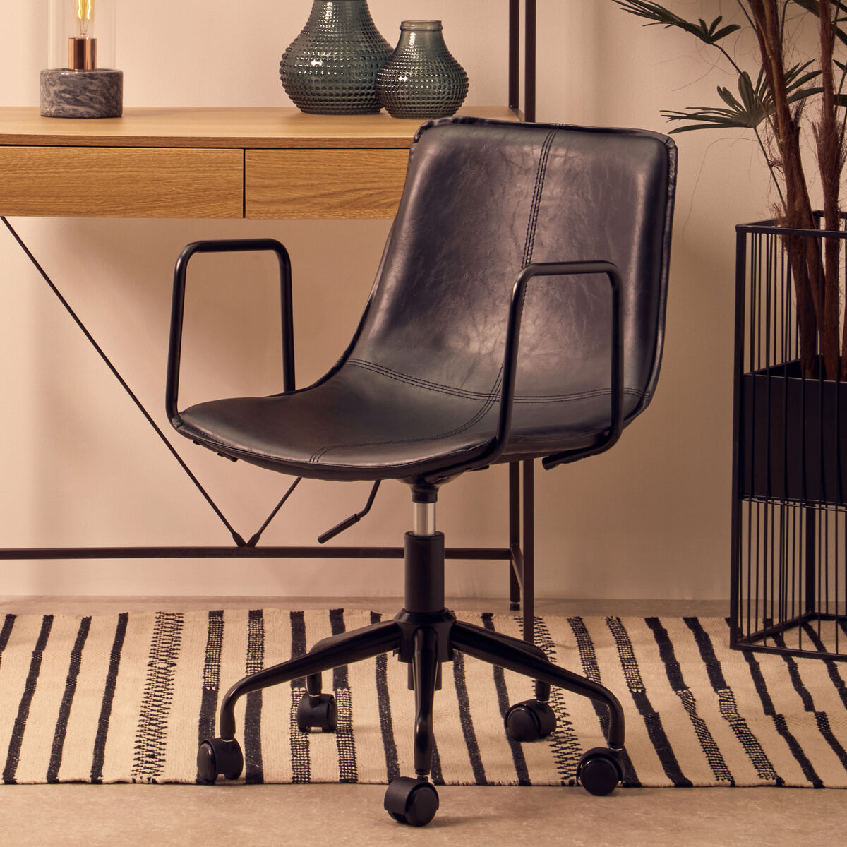 Black office chair in a room with a desk and decorative items.