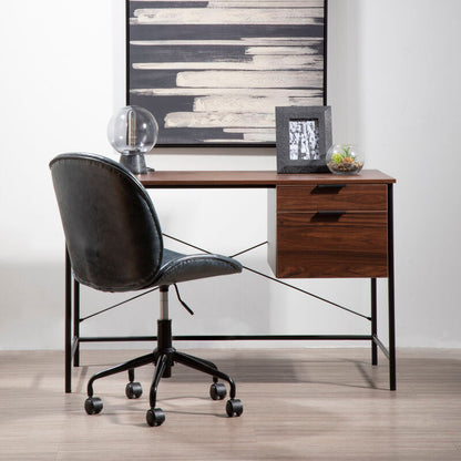 Modern office desk with black chair, framed artwork, and decorative items against a white wall.