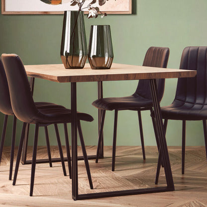 Dining room setup with a wooden table and four chairs against a green wall.