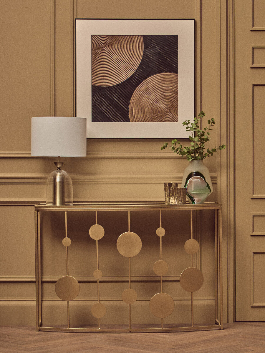 Decorative console table with lamp and framed artwork in a room with beige walls.