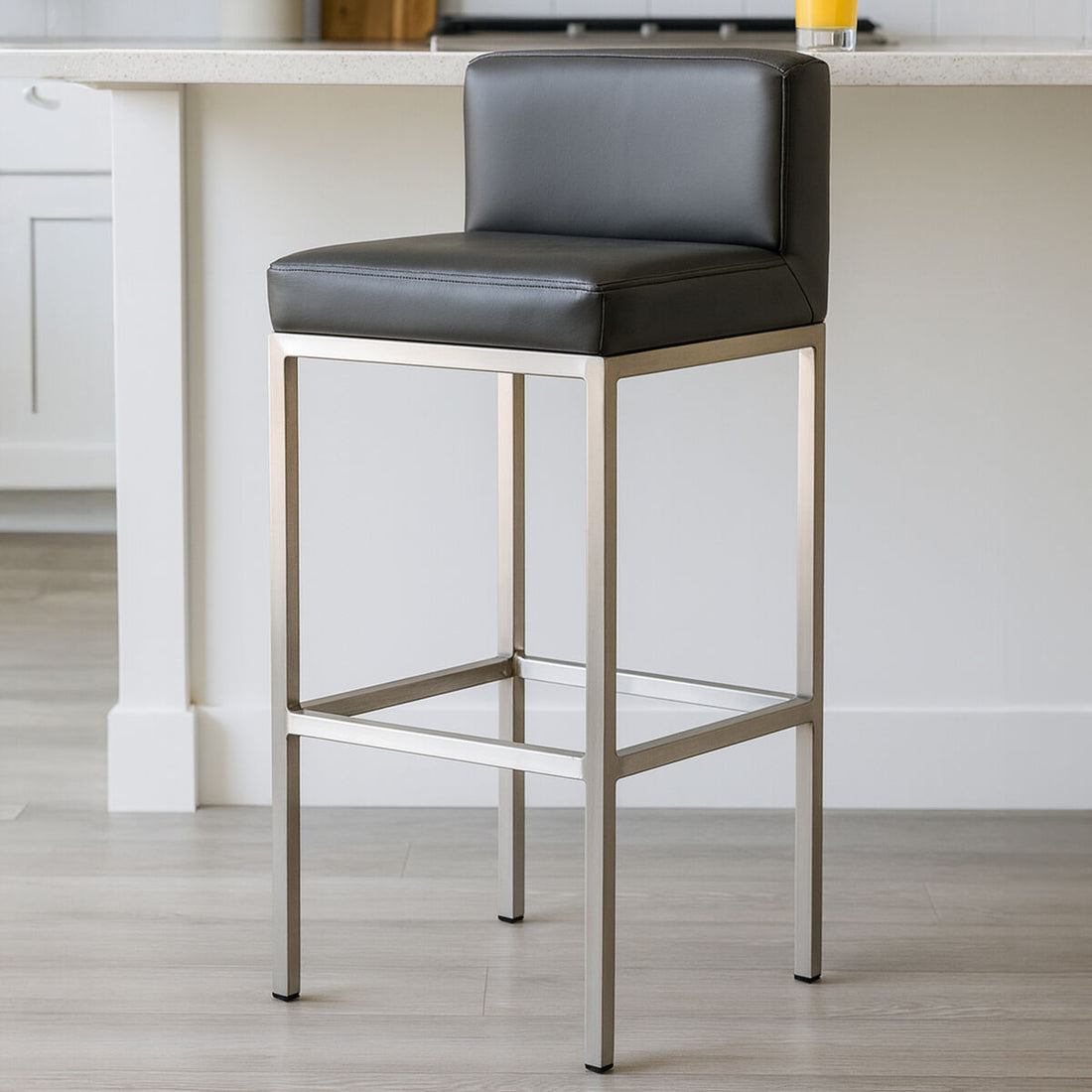 Bar stool with black cushioned seat and metal frame in a kitchen setting