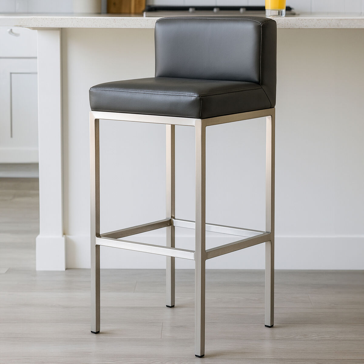 Bar stool with black cushioned seat and metal frame in a kitchen setting