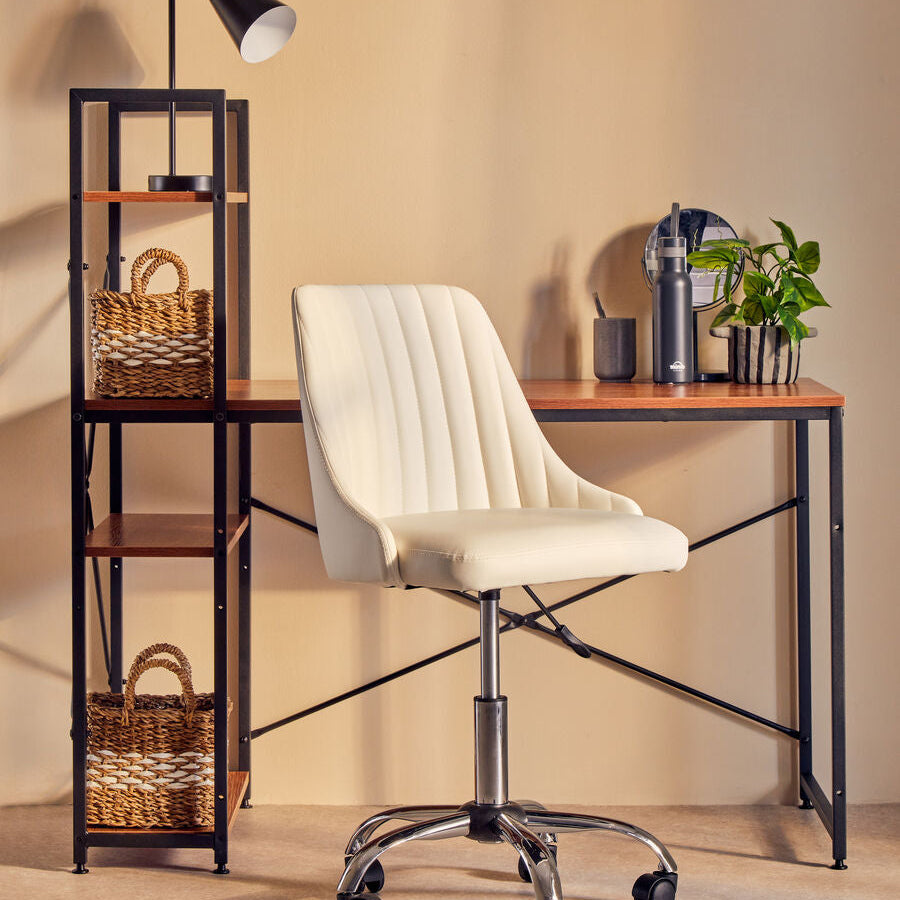 White office chair in front of a wooden desk with a lamp and shelves.