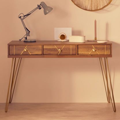 Wooden desk with gold accents against a beige wall