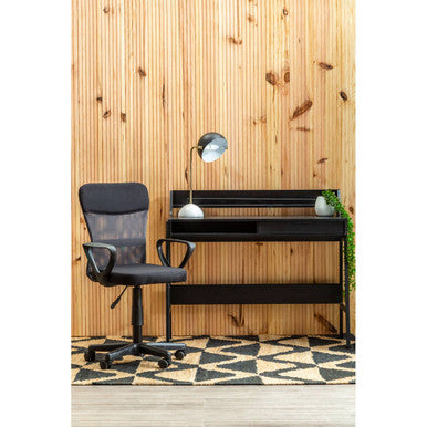 Black office chair and desk against a wooden wall with a geometric patterned floor.