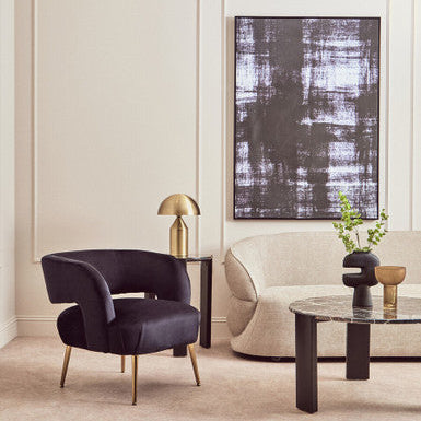 Modern living room with a dark purple armchair, beige sofa, and abstract art on the wall.