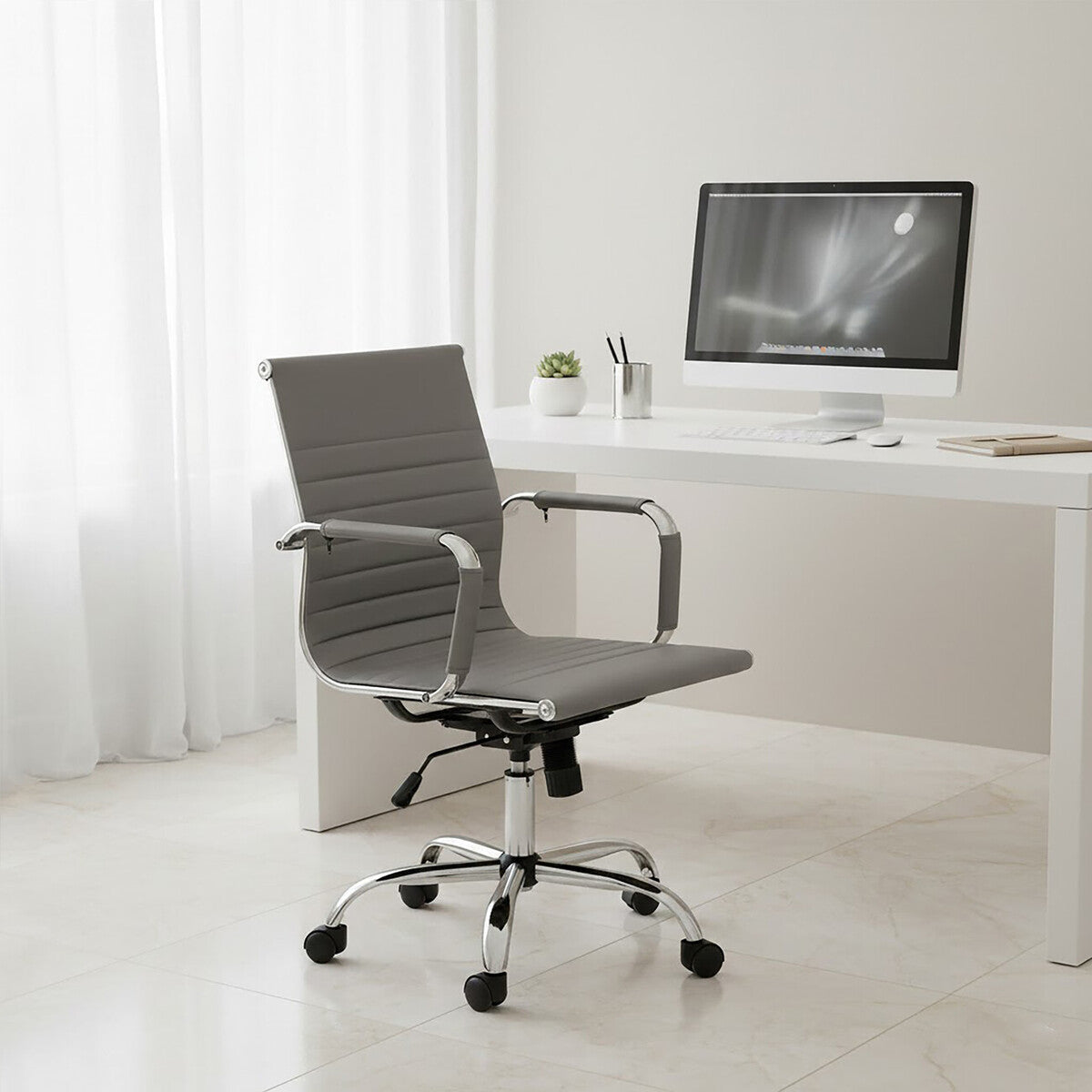 Modern office chair in front of a white desk with a computer setup.