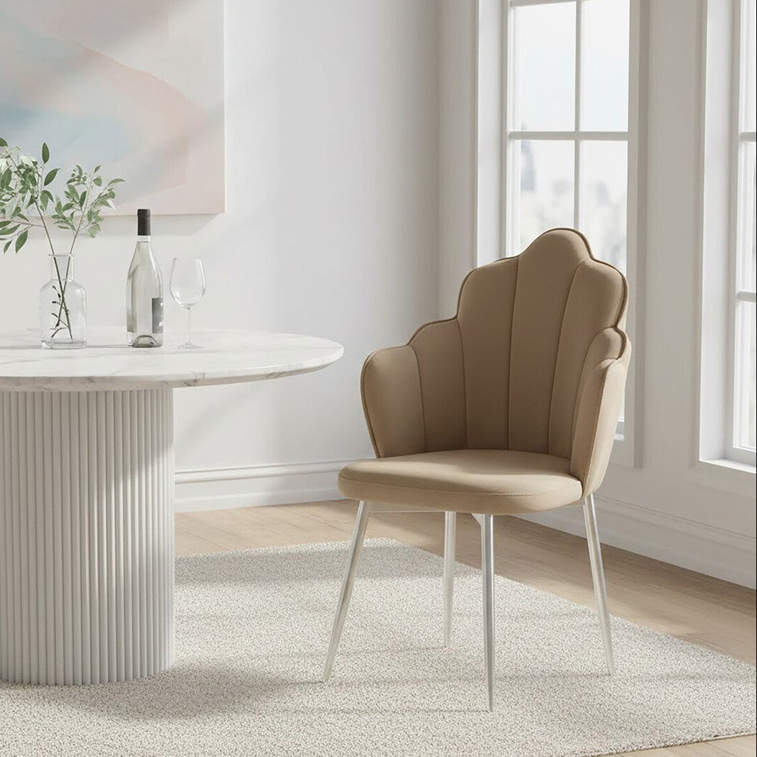 Beige chair next to a round white table in a bright room with large windows.