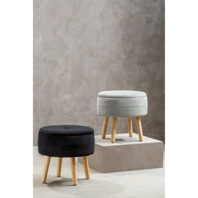 Two stools, one black and one gray, with wooden legs against a textured wall.