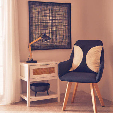 Navy chair with wooden legs in a room with a lamp and framed artwork on the wall.