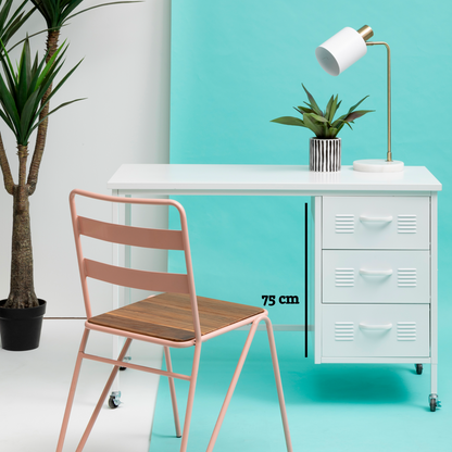 Modern desk with white surface, lamp, and plant against a turquoise wall with a pink chair.