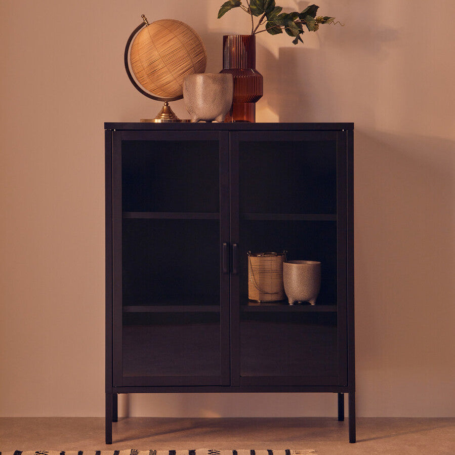 Black cabinet with decorative items against a beige wall