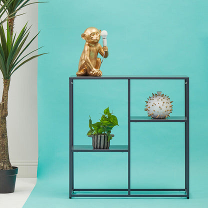 Decorative shelf with a gold monkey figurine, potted plant, and clock against a turquoise wall.
