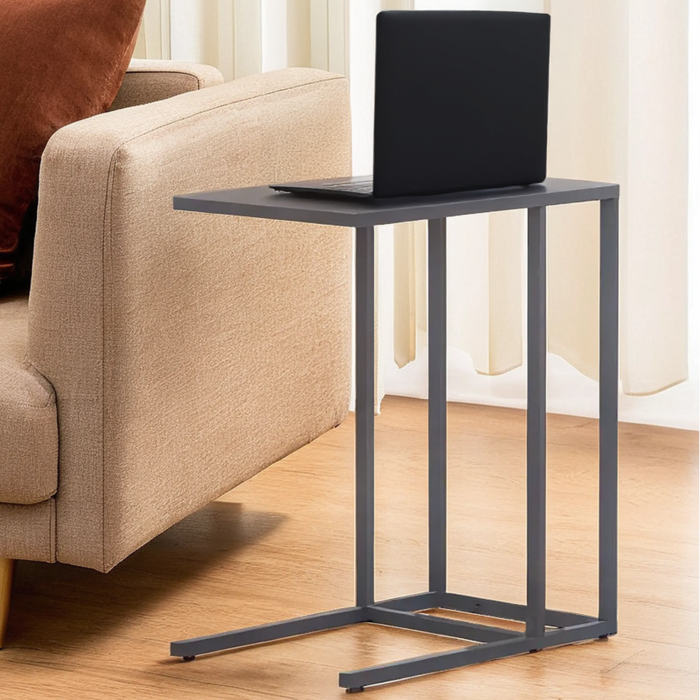 Black side table with a laptop on it next to a beige sofa in a living room.