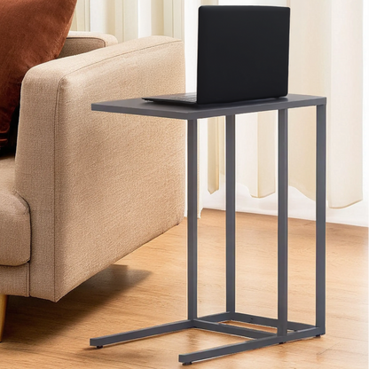Black side table with a laptop on it next to a beige sofa in a living room.
