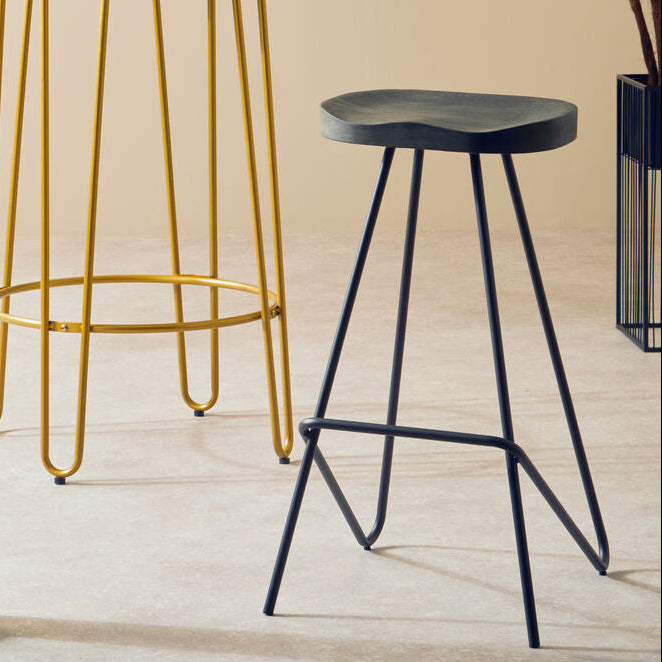 Two bar stools with different metal legs in a room with a plant and open door.