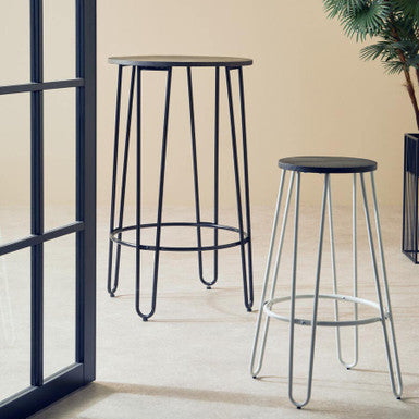 Two black bar stools with metal legs on a light wooden floor against a beige wall.