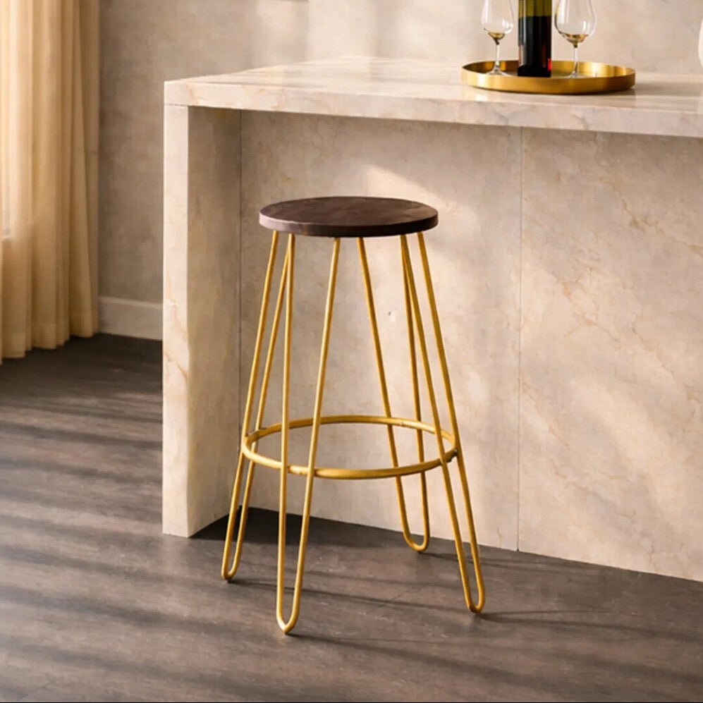 Bar stool with gold legs and wooden seat in a modern interior setting.