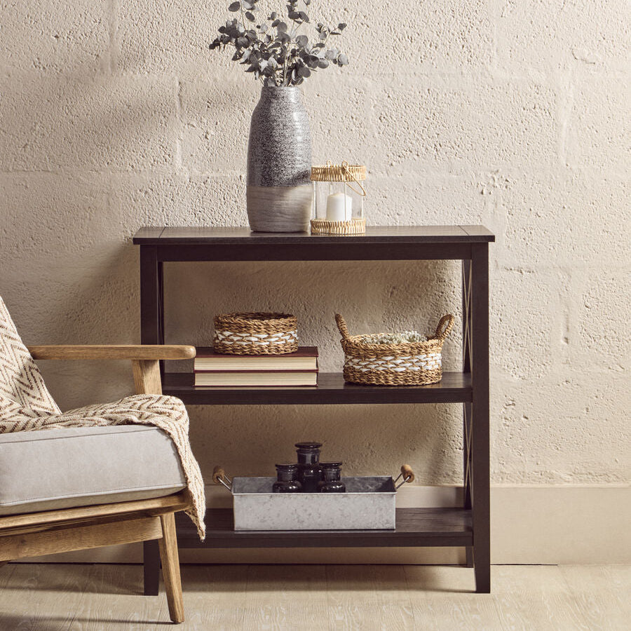 Dark wooden side table with decorative items against a beige wall
