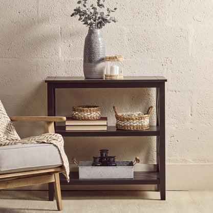 Dark wooden side table with decorative items against a beige wall